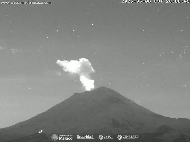 A nighttime grayscale image shows a volcano erupting a plume of smoke under a starry sky.