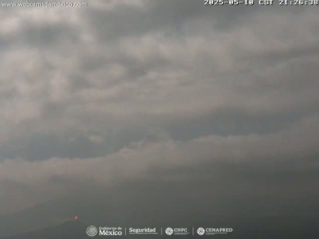 A distant, hazy mountain is barely visible beneath a mostly cloudy, overcast sky.