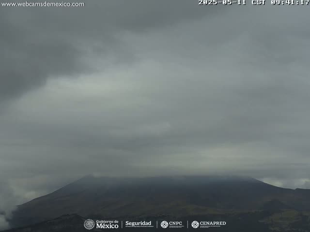 A mostly cloudy sky obscures a distant, dark mountain range.