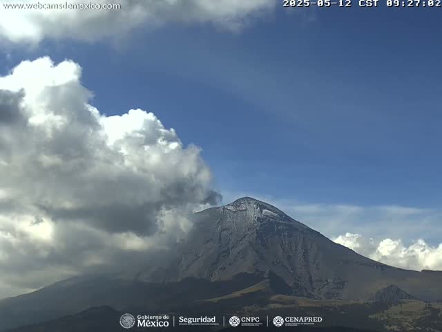 A partly cloudy sky is visible over a snow-capped mountain.