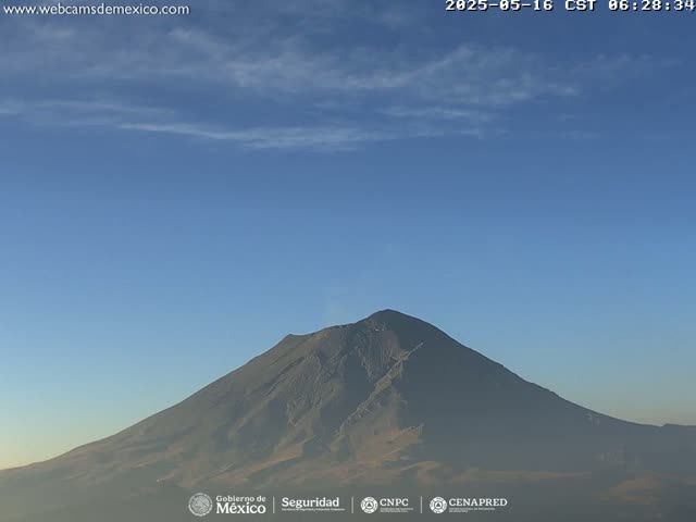 A large, dark mountain is visible under a mostly clear, light blue sky with a few wispy clouds.