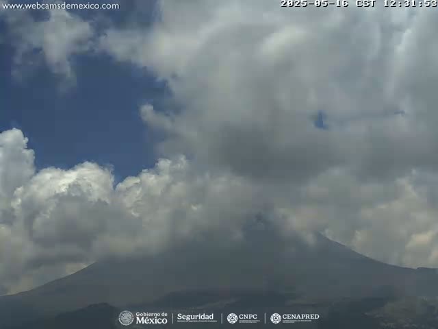 A partly cloudy day reveals a large, dark mountain partially obscured by clouds.