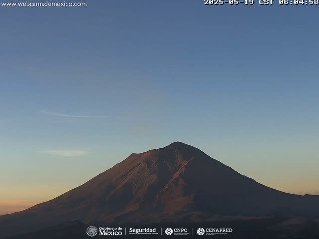 A large, dark mountain is silhouetted against a clear, twilight sky.