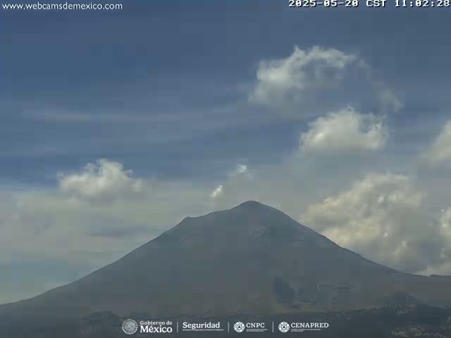 A large, dark mountain is visible under a mostly clear sky with scattered cumulus clouds.