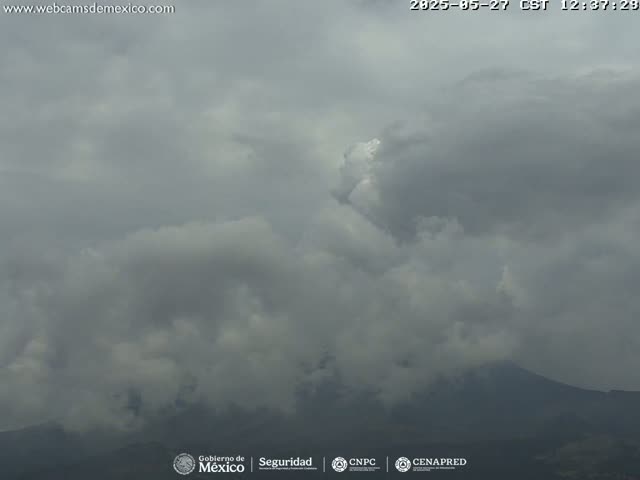 A mostly cloudy sky obscures a distant mountain range under overcast conditions.