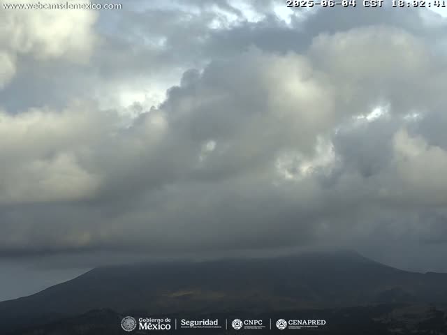 A mostly cloudy sky hangs over a dark, distant mountain range.