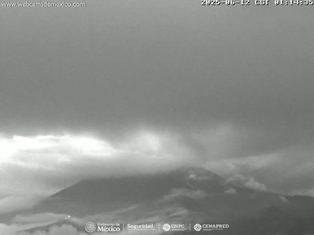 A grayscale image shows a mountain partially obscured by clouds under an overcast sky.