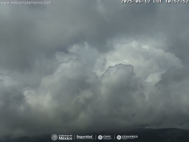 A mostly cloudy sky with dark gray and white cumulus clouds obscures the horizon.