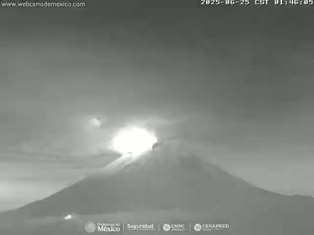 A grayscale image shows a volcano erupting under a mostly cloudy sky.