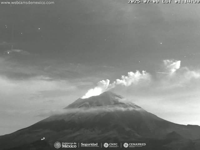 A grayscale image shows a volcano erupting under a mostly clear night sky.