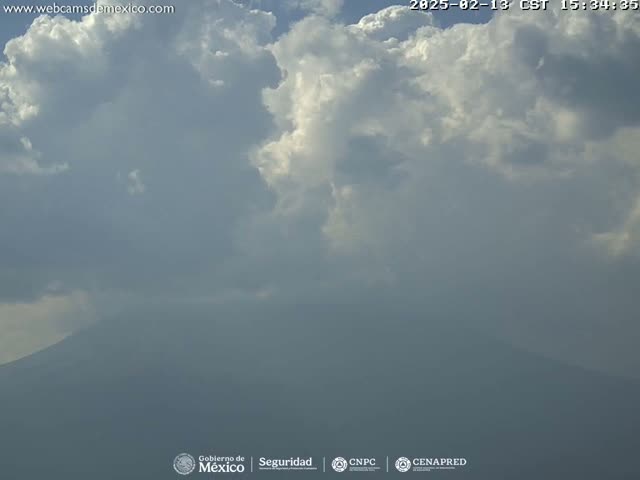 A hazy mountain is visible beneath a mostly cloudy sky.