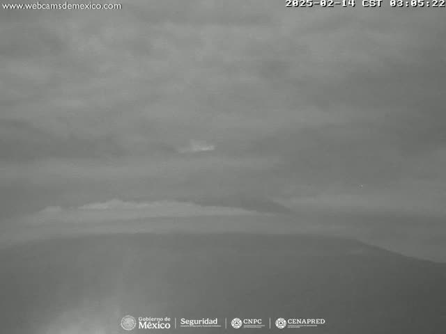 A mostly cloudy, overcast sky is visible over a distant, dark mountain range.