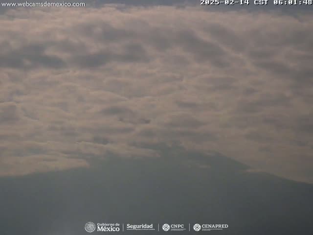 A hazy mountain range is visible beneath a mostly cloudy sky.