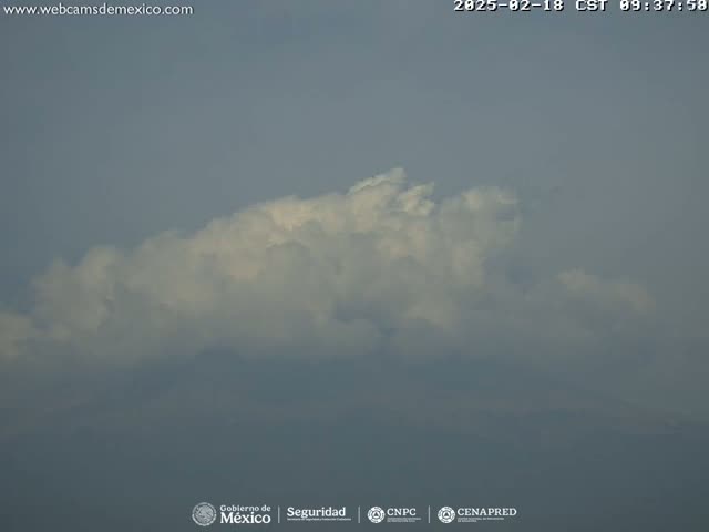 A large, fluffy white cloud formation dominates a hazy, overcast sky.