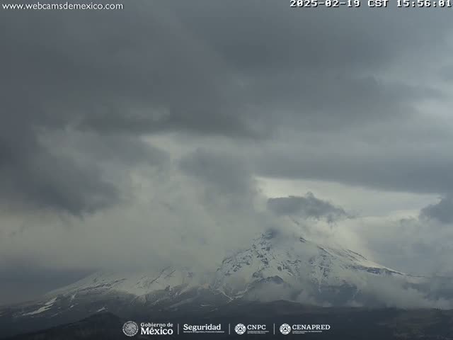 A snow-capped mountain is partially obscured by an overcast sky.