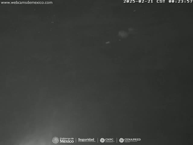 A dark nighttime scene shows a mostly clear sky with a few faint, light-colored objects possibly clouds or distant lights.