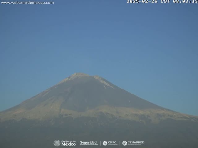 A large, hazy volcano is visible under a clear blue sky.