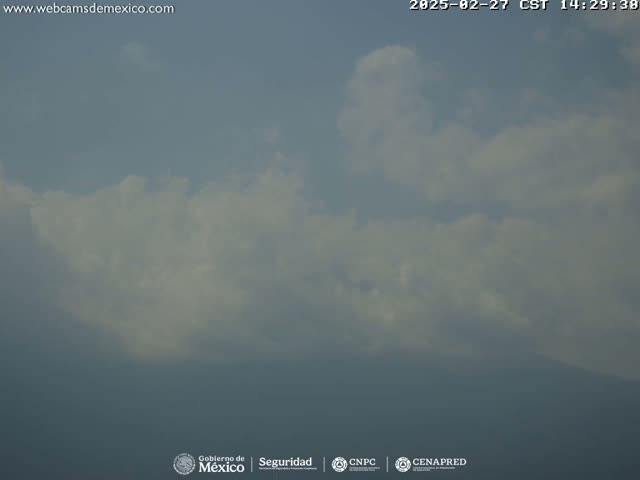 A mostly cloudy sky with hazy conditions obscures a distant mountain range.