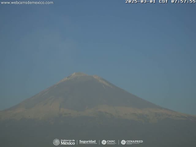 A hazy view of a large, snow-capped mountain under a clear blue sky.