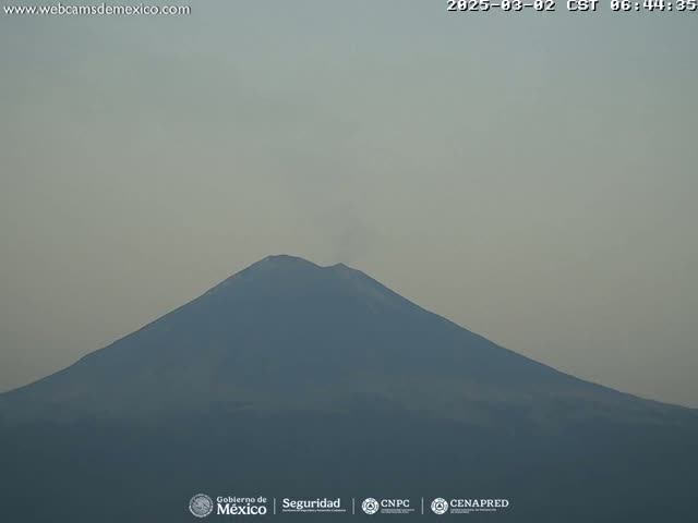 A large, dark-colored mountain is visible under a hazy sky.