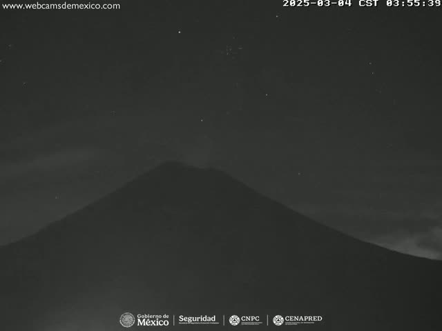 A dark, silhouetted volcano is visible under a mostly clear night sky with a few stars.