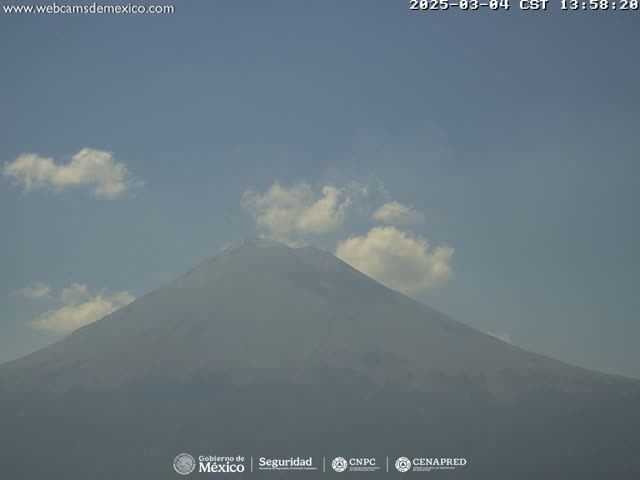 A large, hazy mountain is visible under a mostly clear sky with a few scattered clouds.
