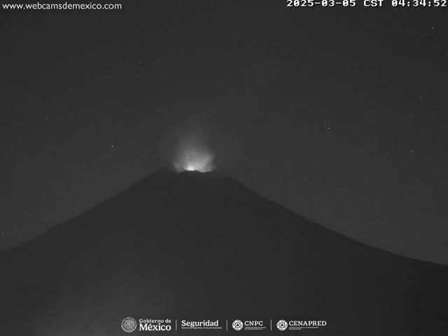 A volcano erupts at night under a clear, starry sky.