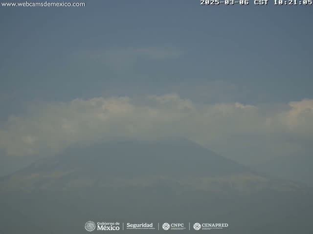 A hazy mountain is visible under a mostly cloudy sky.