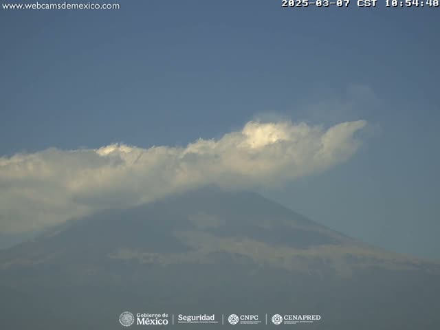 A partly cloudy sky is visible above a large, hazy mountain.