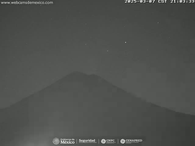 A dark, hazy night scene shows a large, silhouetted mountain under a clear, starry sky.