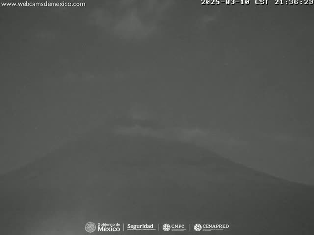A dark, overcast sky covers a dimly lit, large mountain under nighttime conditions.