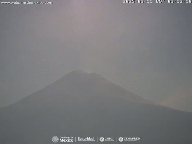 A hazy, muted-light view shows a large, dark mountain shrouded in mist or fog.
