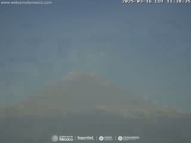 A hazy view shows a large, indistinct landmass under a clear, light-blue sky.