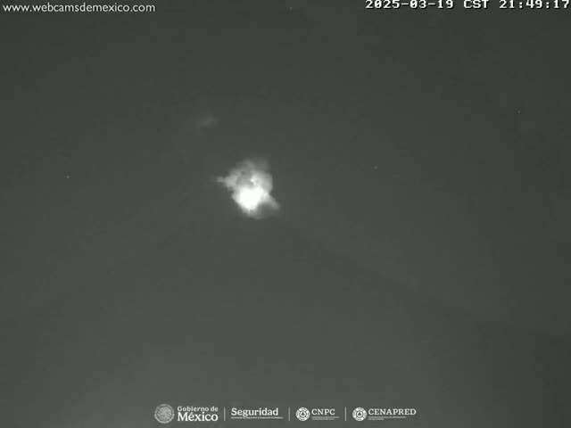 A bright, diffuse light source is visible in a dark night sky.