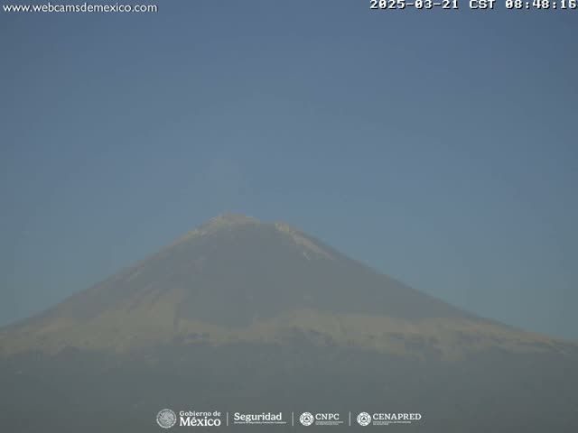 A hazy, distant view of a large, snow-capped mountain is visible under a clear blue sky.