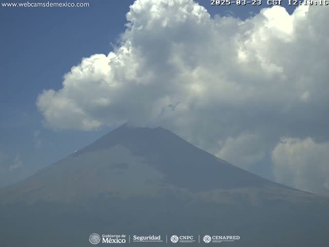 A partly cloudy sky overlooks a large, dark-colored volcano.