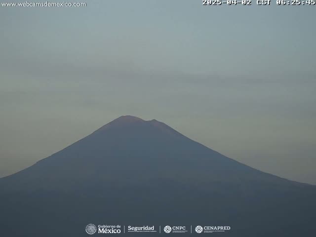 A large, dark-colored mountain is visible under a pale, hazy sky.