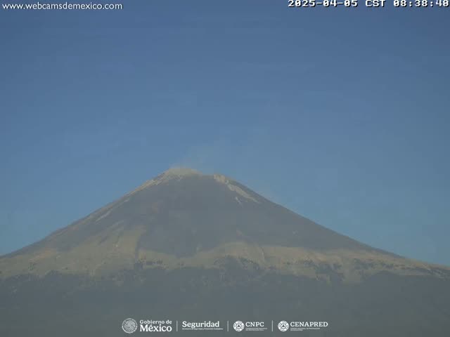 A large, hazy mountain is visible under a clear blue sky.