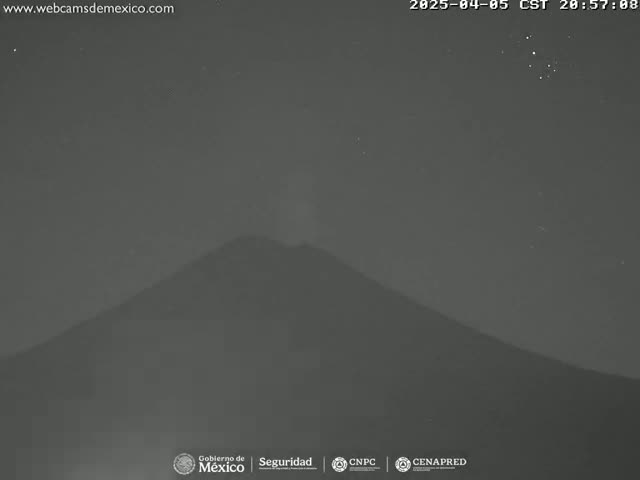 A dark, silhouetted mountain is visible at night under a mostly clear sky with a few stars.