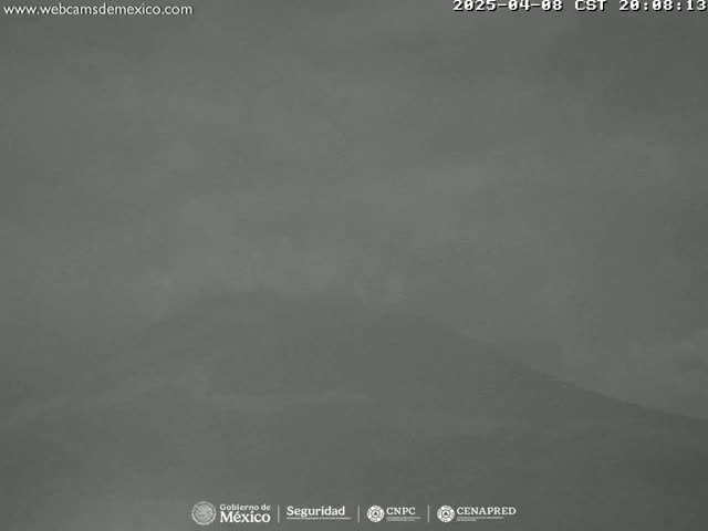 A hazy, overcast view of a mountainous landscape is visible at night.