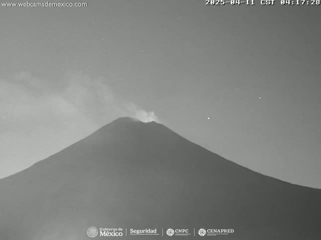 A volcano erupts under a nighttime sky with some clouds.