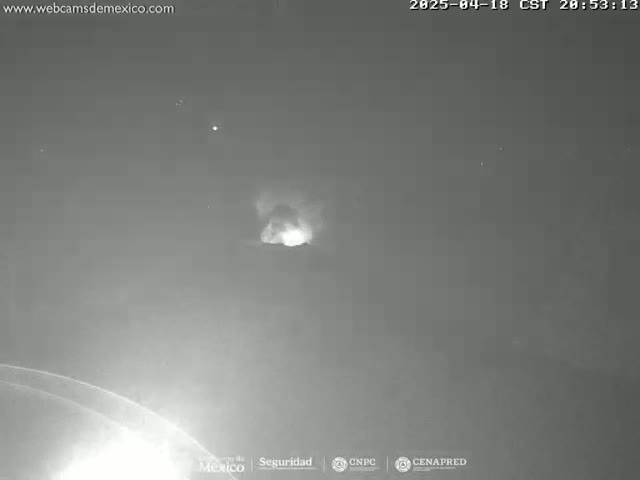 A nighttime, grayscale image shows a bright, hazy glow in the dark sky.