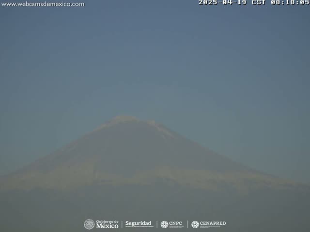 A hazy, distant view of a large mountain under a clear sky.