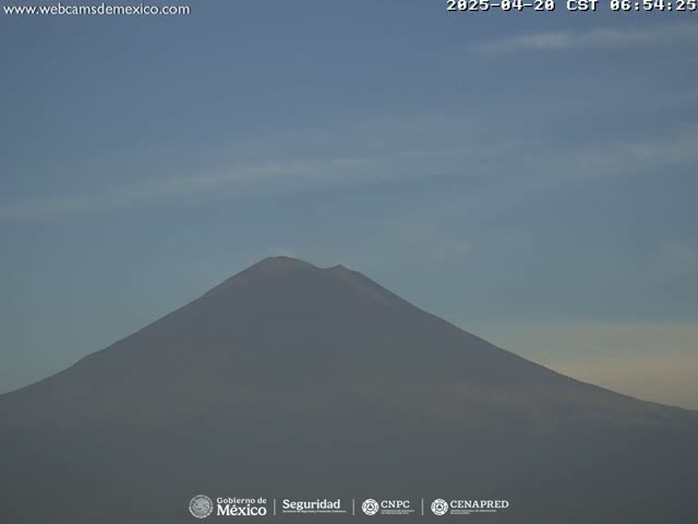 A hazy, dark-colored mountain is visible under a mostly clear sky.
