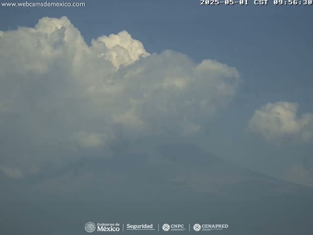 A large, fluffy cumulus cloud formation dominates a mostly clear sky over a hazy mountain range.