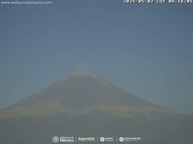 A hazy, distant view of a large mountain under a clear blue sky.