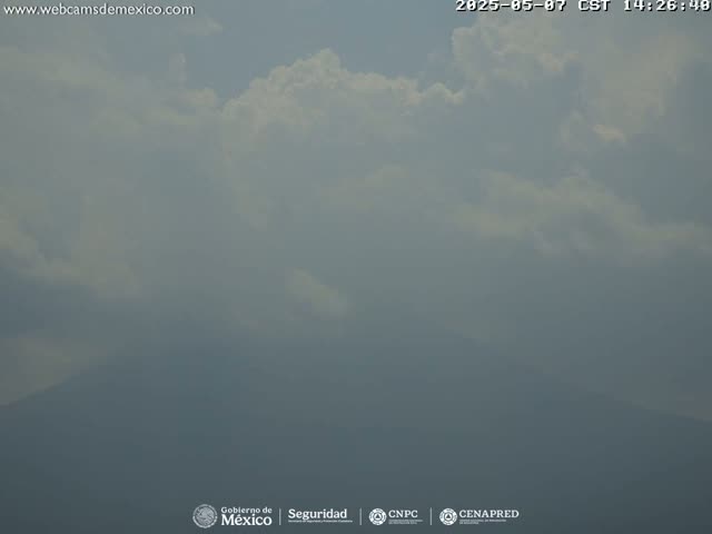 A hazy view of a mountain range under a partly cloudy sky.