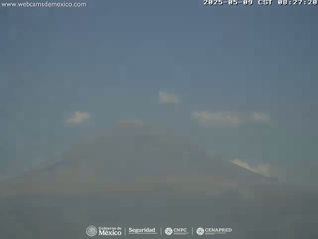 A hazy mountain range is visible under a mostly clear, light-blue sky with a few small clouds.
