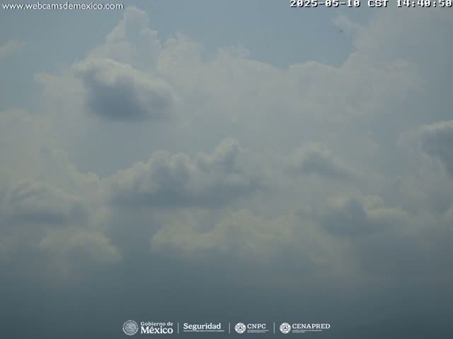A mostly cloudy sky is visible, with fluffy white cumulus clouds scattered across a light blue background.