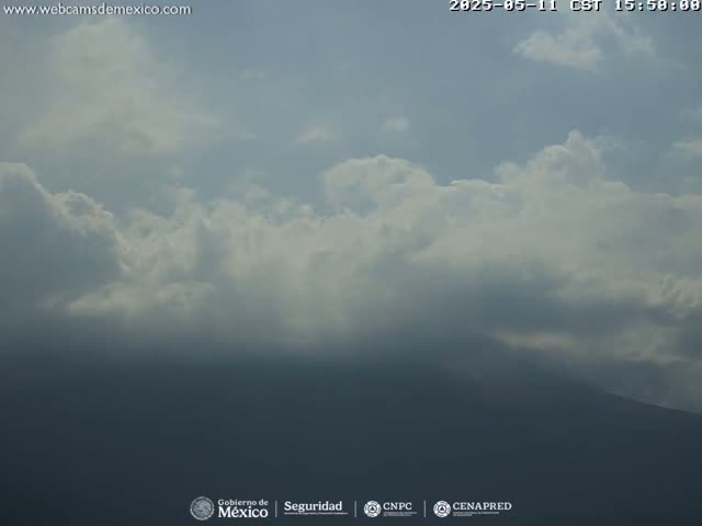 A partly cloudy sky obscures a distant, dark mountain range.